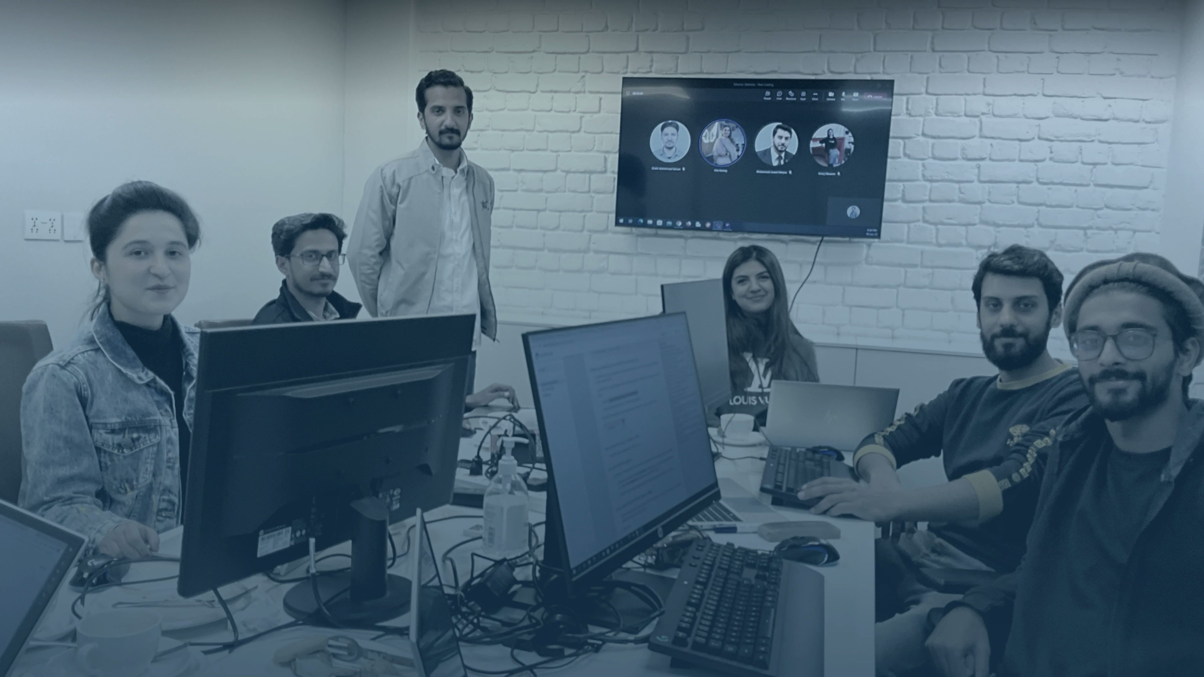 A team of developers at MRS Technologies working together on a project and smiling - Some members are also seen doing remote work | MRS Technologies Pakistan